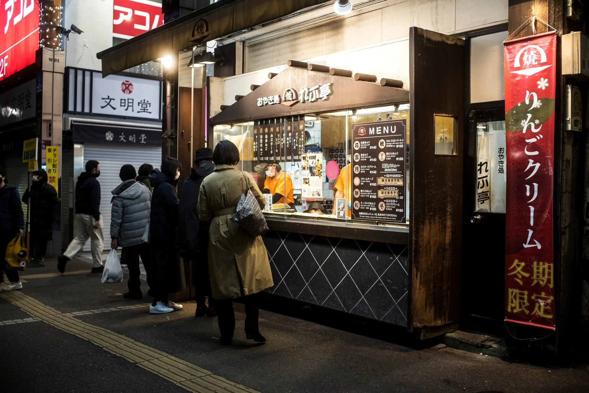 Hands shaping takoyaki batter on a cast iron griddle in a small Osaka kitchen